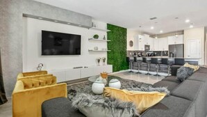 Een moderne woonkamer met een bank, een salontafel en een aan de muur bevestigde televisie.