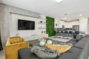 Ein modernes Wohnzimmer mit einer Couch, einem Couchtisch und einem an der Wand befestigten Fernseher.