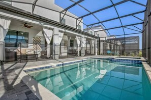 Ein Innenpool mit Glasdecke, Deckenventilator und einer Sitzecke mit gemustertem Wanddesign.