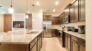 A modern kitchen with granite countertops, stainless steel appliances, and dark wood cabinets. - Family-friendly Townhouse w/ Private Pool & Game Room (Clermont)