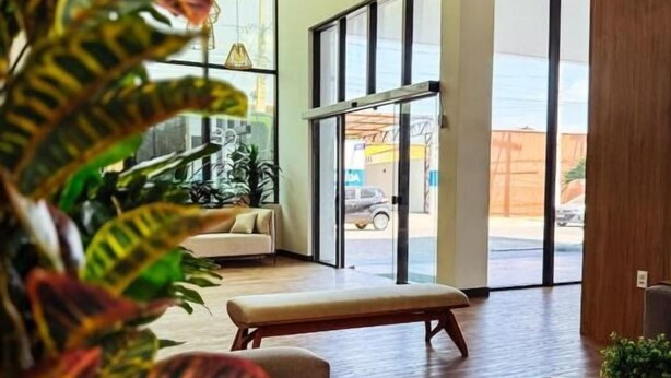 A modern interior with a sofa, a coffee table, and a large window with a view of the street. - Citi Executivo Hotel (Parnaíba)