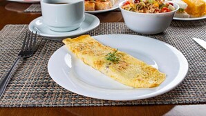 A breakfast setting with an omelette, coffee, and various side dishes on a table. - Citi Executivo Hotel (Parnaíba)