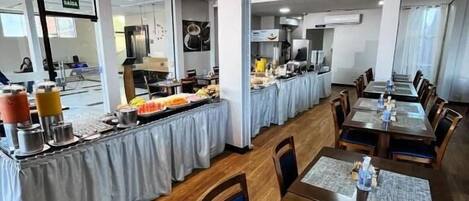 Un comedor con mesas, sillas y una mesa de buffet.