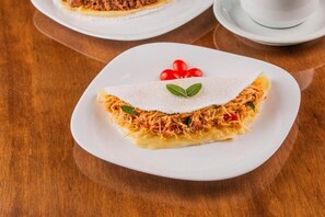Ein Teller mit Speise, eine Tasse und ein Untertasse auf einem Holztisch.