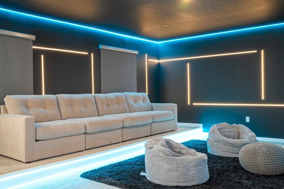 A modern living room with a sofa, bean bags, and geometric wall lighting.