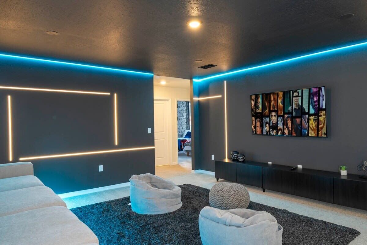 A modern living room with a dark wall, a large abstract painting, and a black entertainment unit.