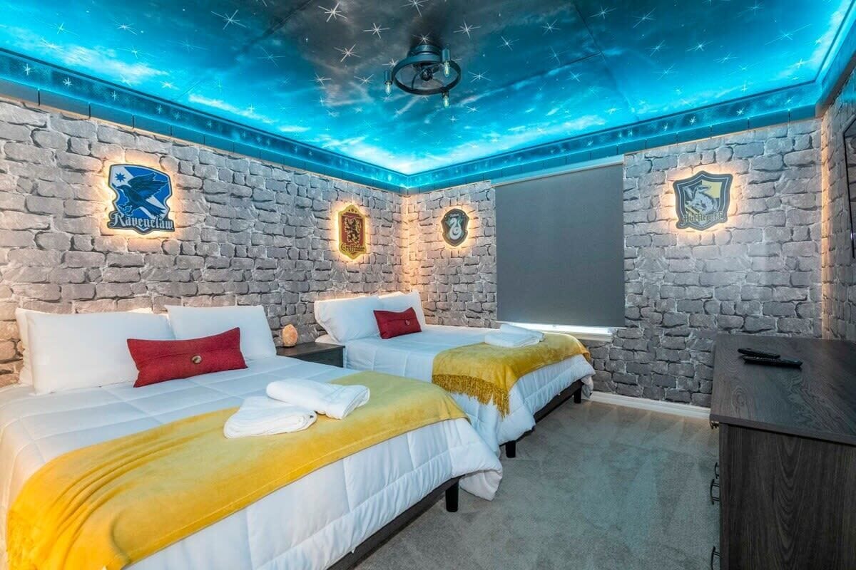 A hotel room with two beds, stone walls, and a ceiling with a starry light design.
