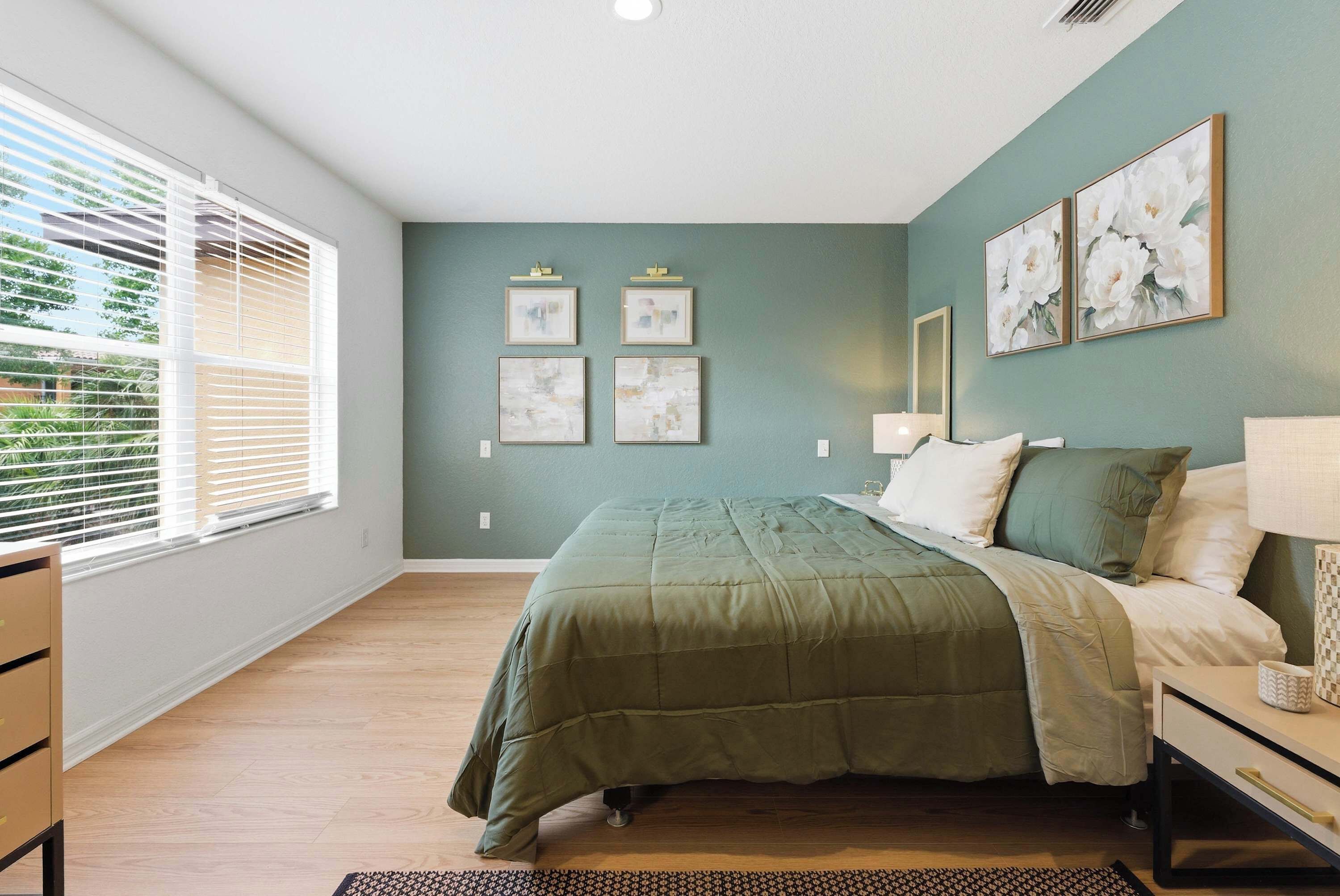 A bedroom with a bed, a nightstand, a lamp, and artwork on the wall.