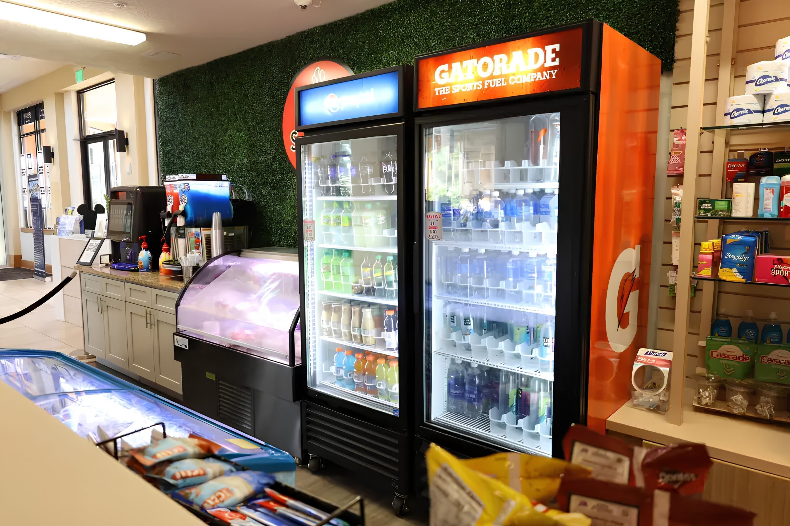 A Gatorade refrigerator, a self-service beverage dispenser, and a refrigerated display case with various products.