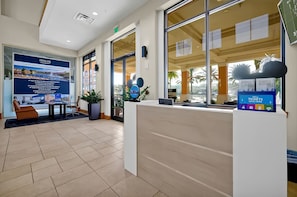 A reception area with a reception desk, a large poster, and a view of the outside. - Modern Family 4BR Townhome Near Disney in Orlando (Kissimmee)