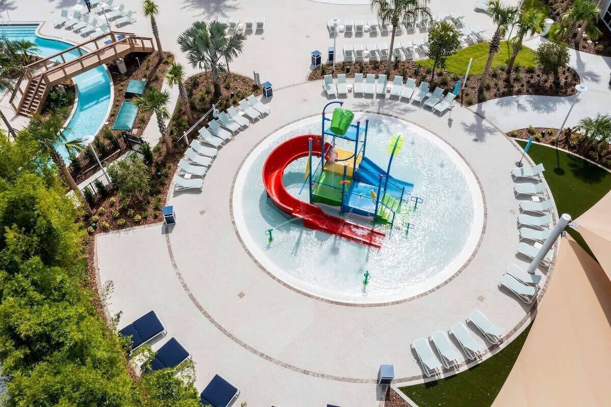 Parque acuático con un tobogán central, sillas de descanso alrededor y una zona de piscina.