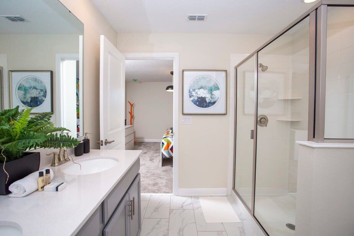 A modern bathroom with a glass shower enclosure, a double sink vanity, and a large mirror.