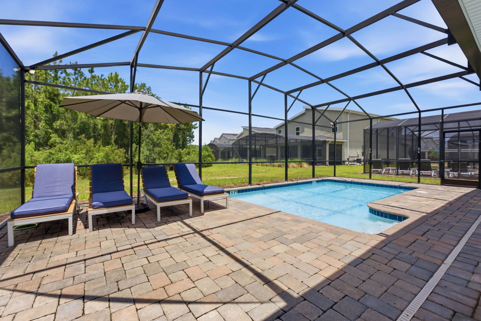 Piscina ao ar livre coberta, com espreguiçadeiras e um guarda-sol, cercada por uma grade de metal.