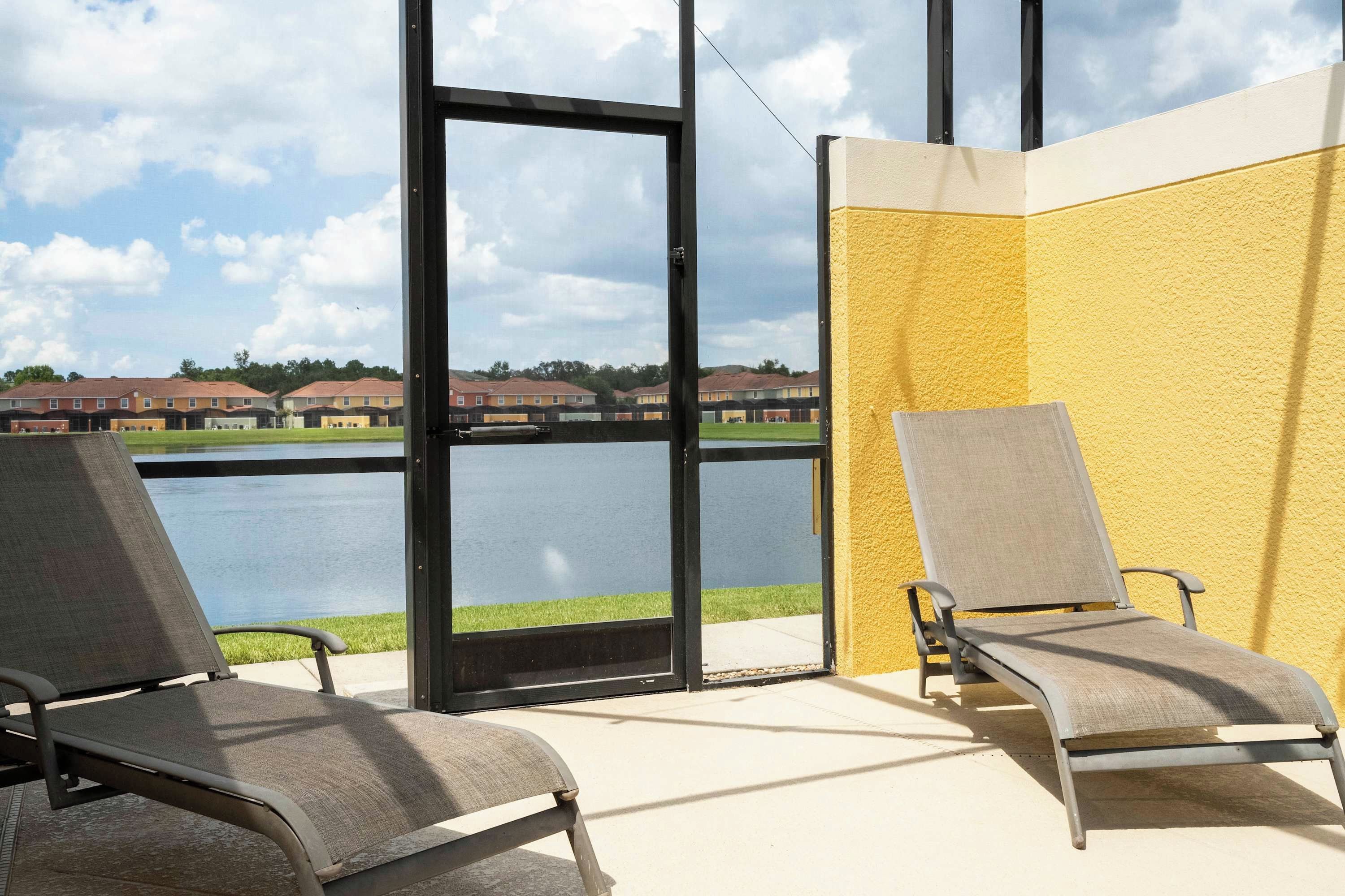 A balcony with two chairs and a view of a lake and buildings in the distance.