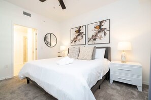 Ein Schlafzimmer mit einem Bett, Nachttischen, einem Spiegel und abstrakter Wandkunst.
