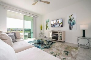 Ein modernes Wohnzimmer mit einer Couch, einem Glastisch, einem Fernseher und Blick durch eine Schiebetür.