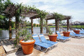 A patio area with lounge chairs, potted plants, and a pergola structure. - Disney Stay w/ Private Pool + Family Fun Sleeps 9 (Kissimmee)