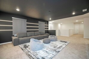 A modern living room with a grey sofa, two bean bags, and a patterned rug. - Luxury Family Home w/ Private Pool & Clubhouse (Davenport)