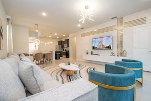 Ein modernes Wohnzimmer mit einer Couch, einem Hocker und einem Essbereich mit Stühlen und einem Tisch.