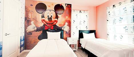 Ein Hotelzimmer mit zwei Betten, einem Wandbild mit Micky Maus und Micky-Maus-Dekoration.