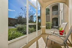 Ein Balkon mit einem Stuhl, einem Blumentopf und Blick auf ein Gebäude und Grünflächen.