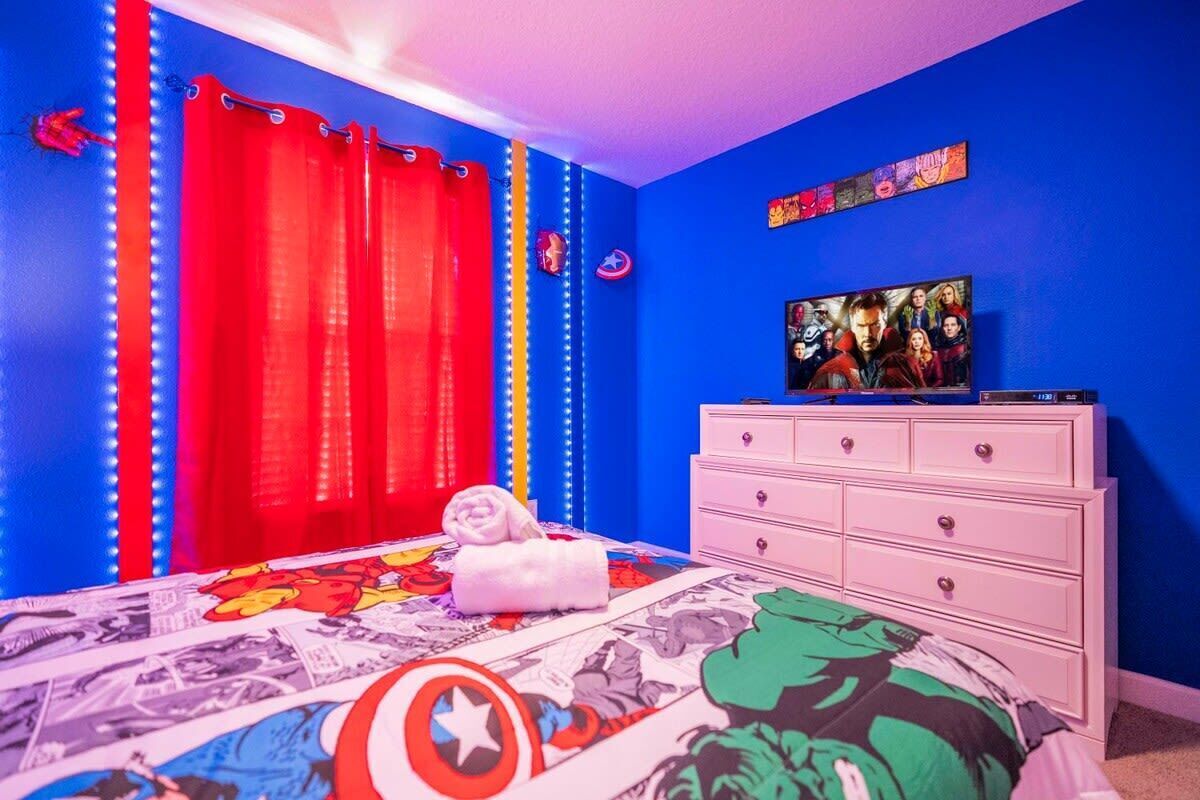 A bedroom with a bed, curtains, a dresser, and a TV.