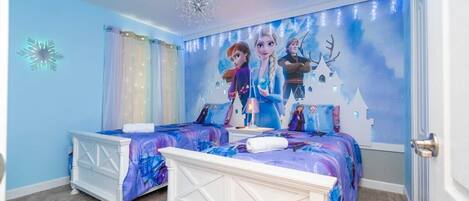 A bedroom with two beds, a chandelier, and a wall mural.