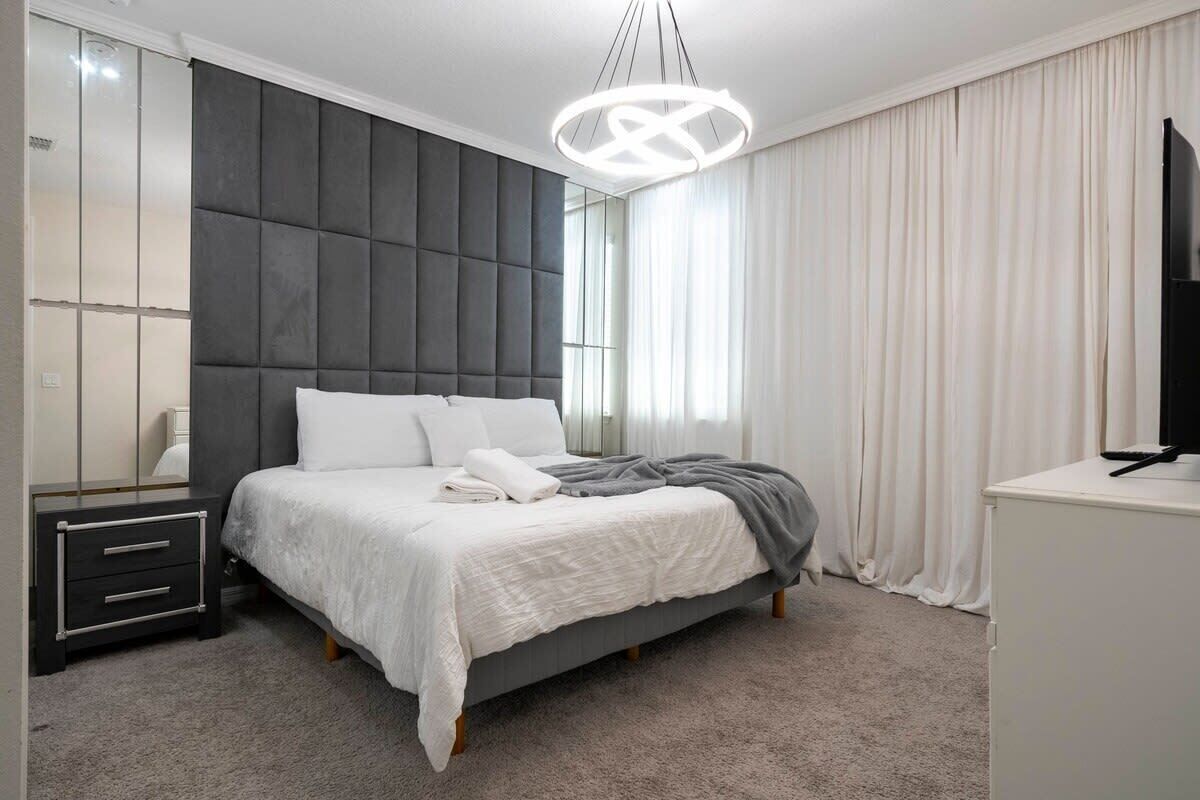 Une chambre à coucher comprenant un lit, des tables de chevet, une commode, un miroir et un téléviseur.