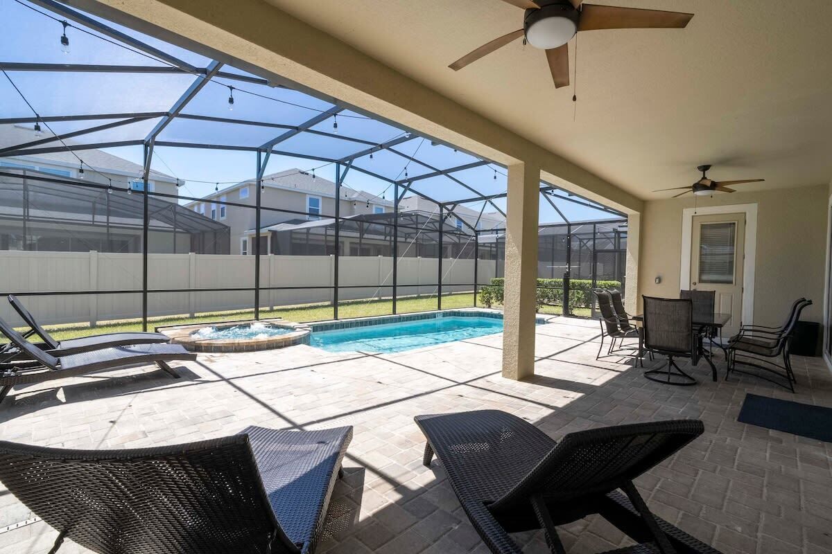 Un patio cubierto con piscina, sillas de descanso y una mesa.