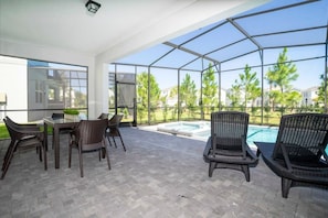 Eine überdachte Terrasse mit Tisch und Stühlen, ein Pool und Blick auf die Umgebung.