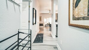 A hallway with a staircase, a dining area, and a kitchen. - Luxurious Family Townhouse With Private Backyard Retreat (Davenport)