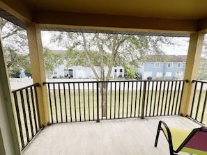 Ein überdachter Balkon mit Blick auf eine Wohngegend, einschließlich Häusern und einem Baum.