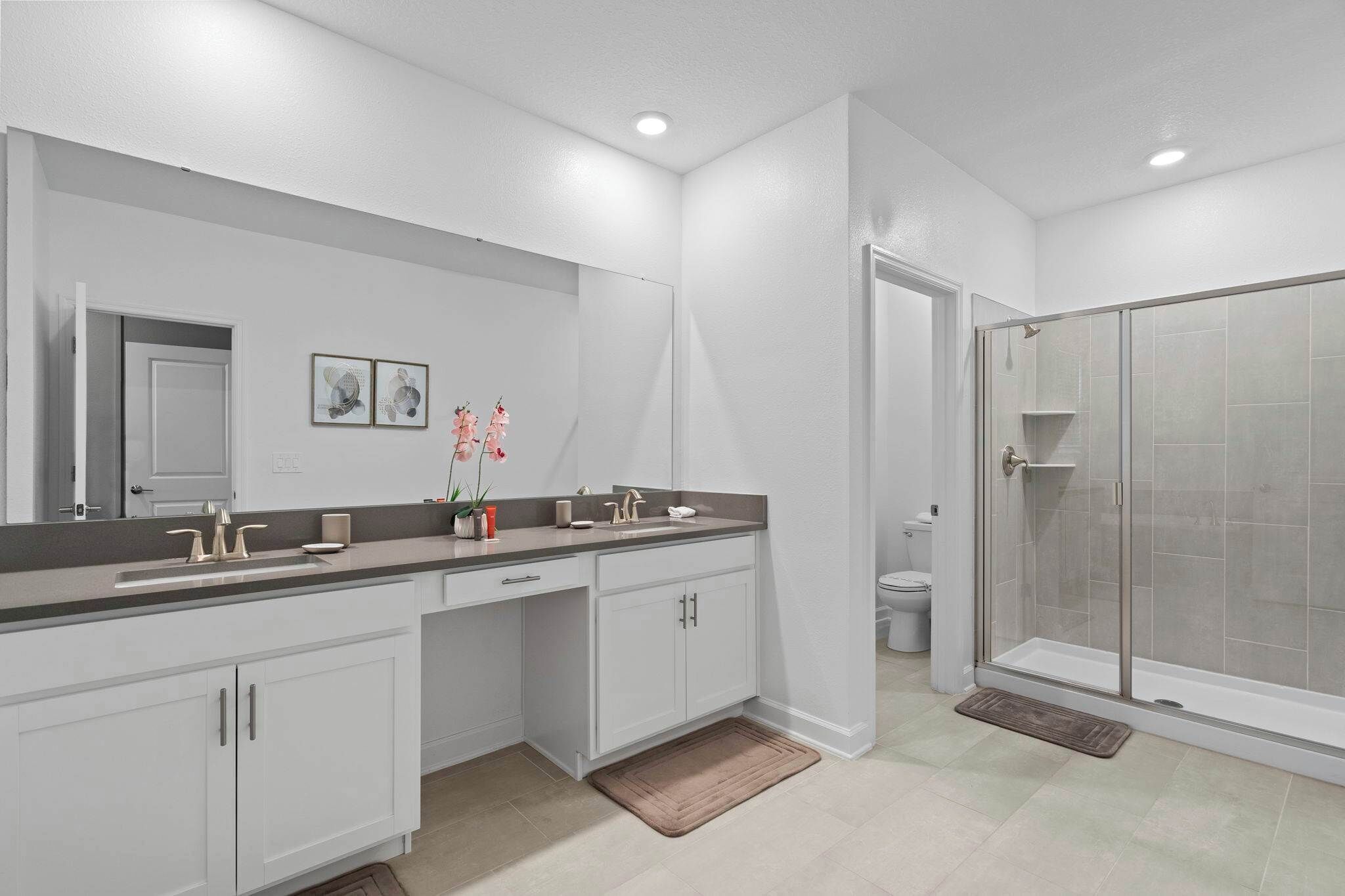 A modern bathroom with a walk-in shower, a large mirror, and a double sink vanity.