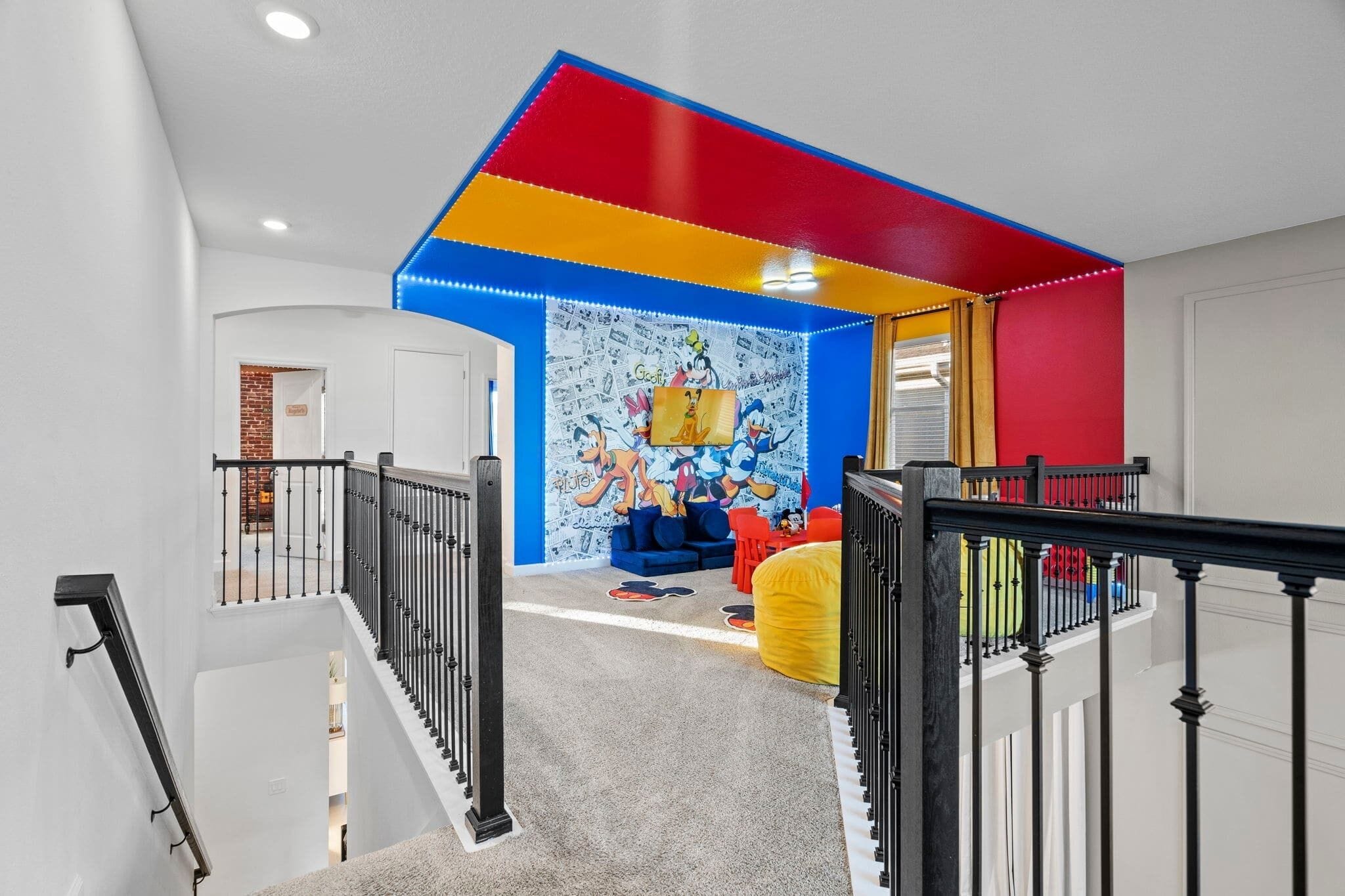 A multi-level home interior with a staircase, a colorful wall mural, and a play area with toys.