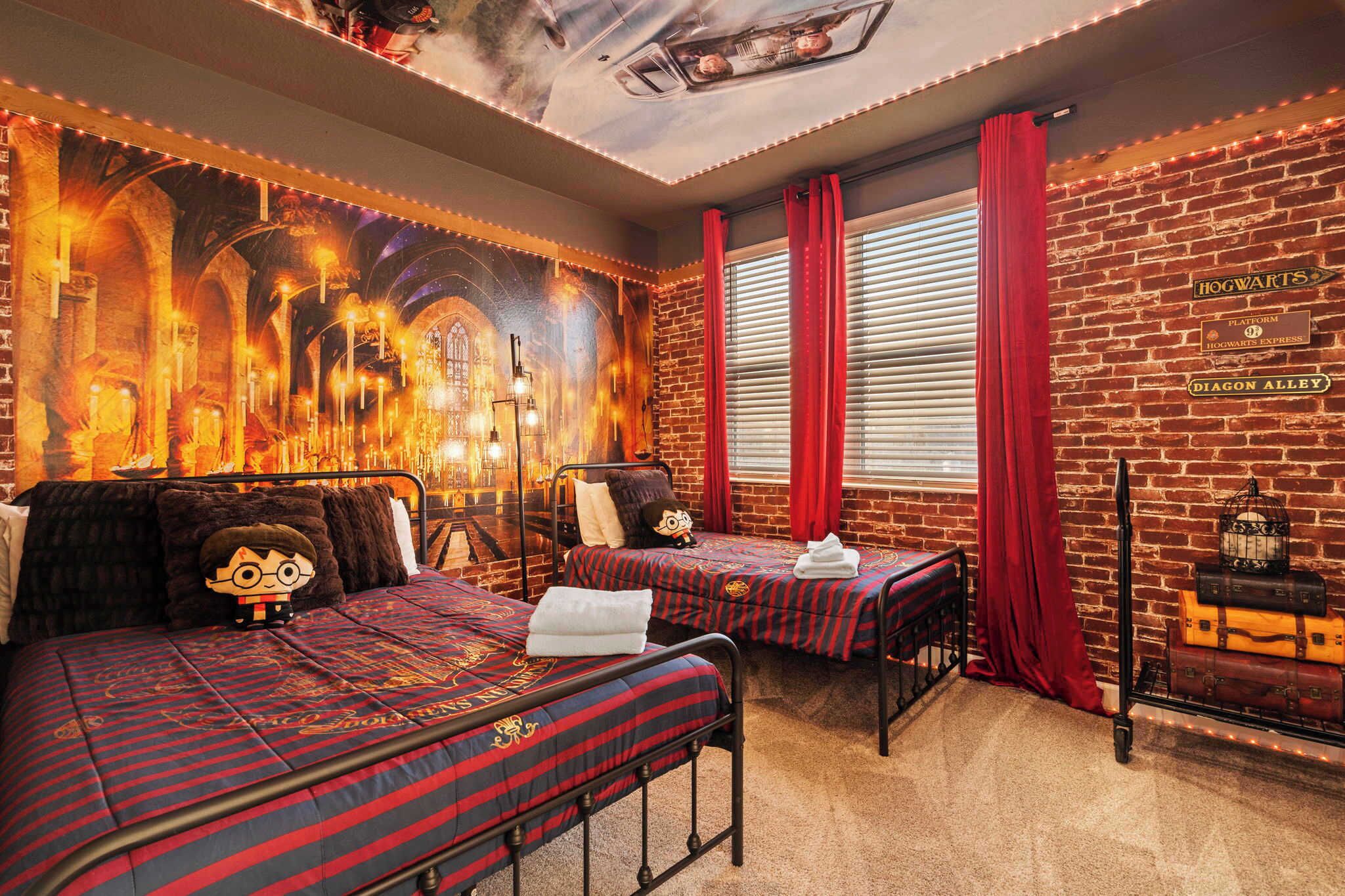 A room with two beds, a brick wall, and a mural of a castle.