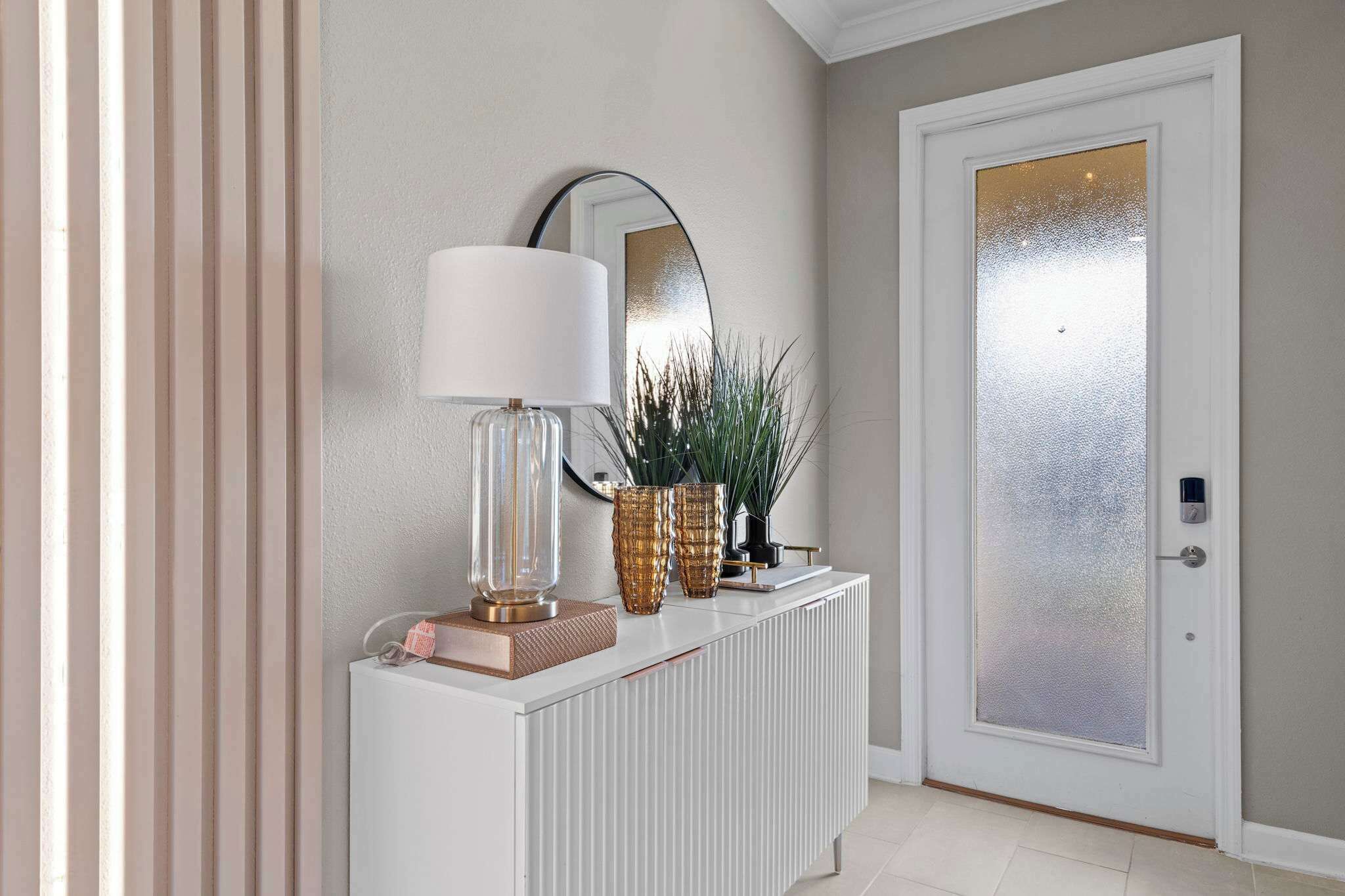 En gang med et hvidt konsolbord, en lampe, dekorative vaser og et spejl.