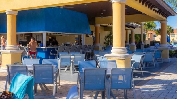 Un espace extérieur aménagé avec des chaises bleues et un bar couvert.