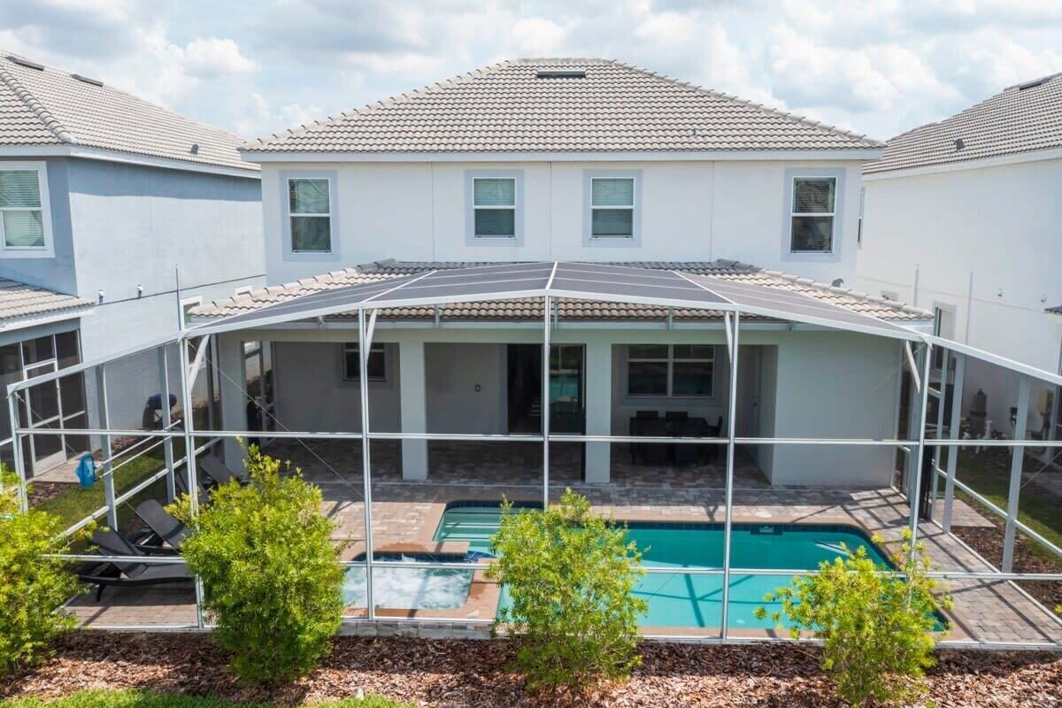 A residential property with a covered patio, a swimming pool, and a clear view of neighboring houses.