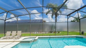A swimming pool with a glass enclosure, lounge chairs, and a view of solar panels. - Family-friendly House With Game Room & Private Pool (Davenport)