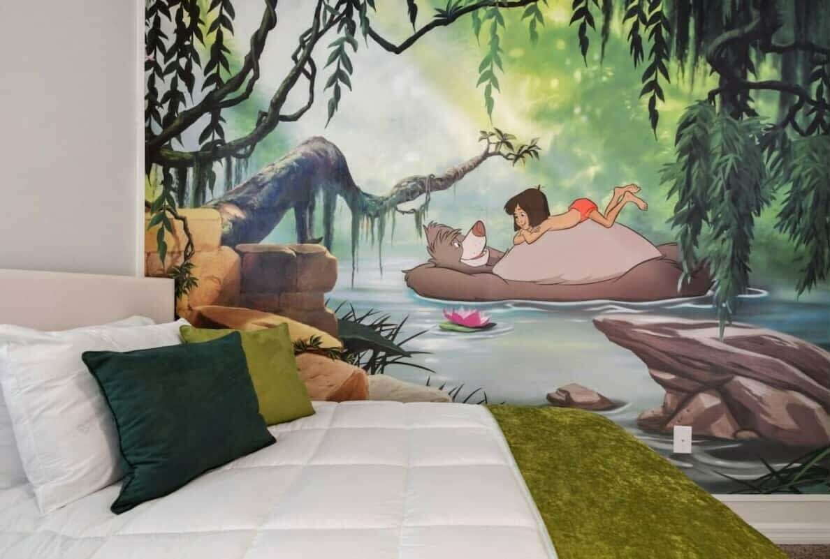 Un dormitorio con un mural de una escena de bosque, una cama con ropa blanca y almohadas.