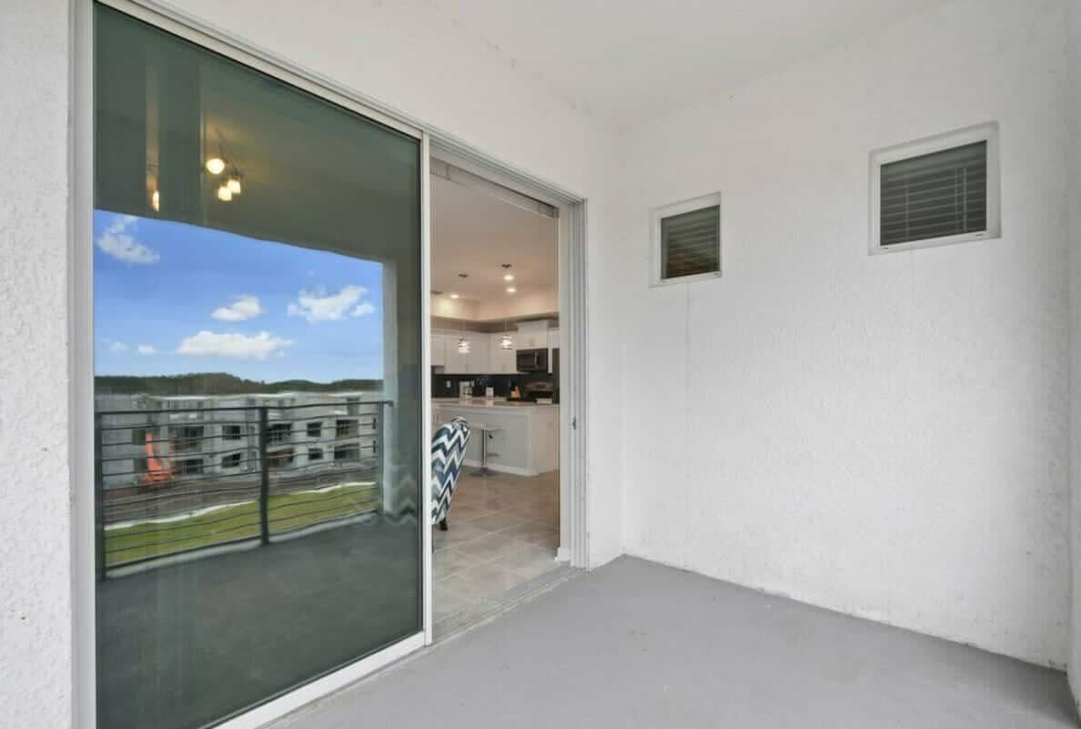 Een balkon met uitzicht op een gebouw, een schuifpui en een klein keukentje.