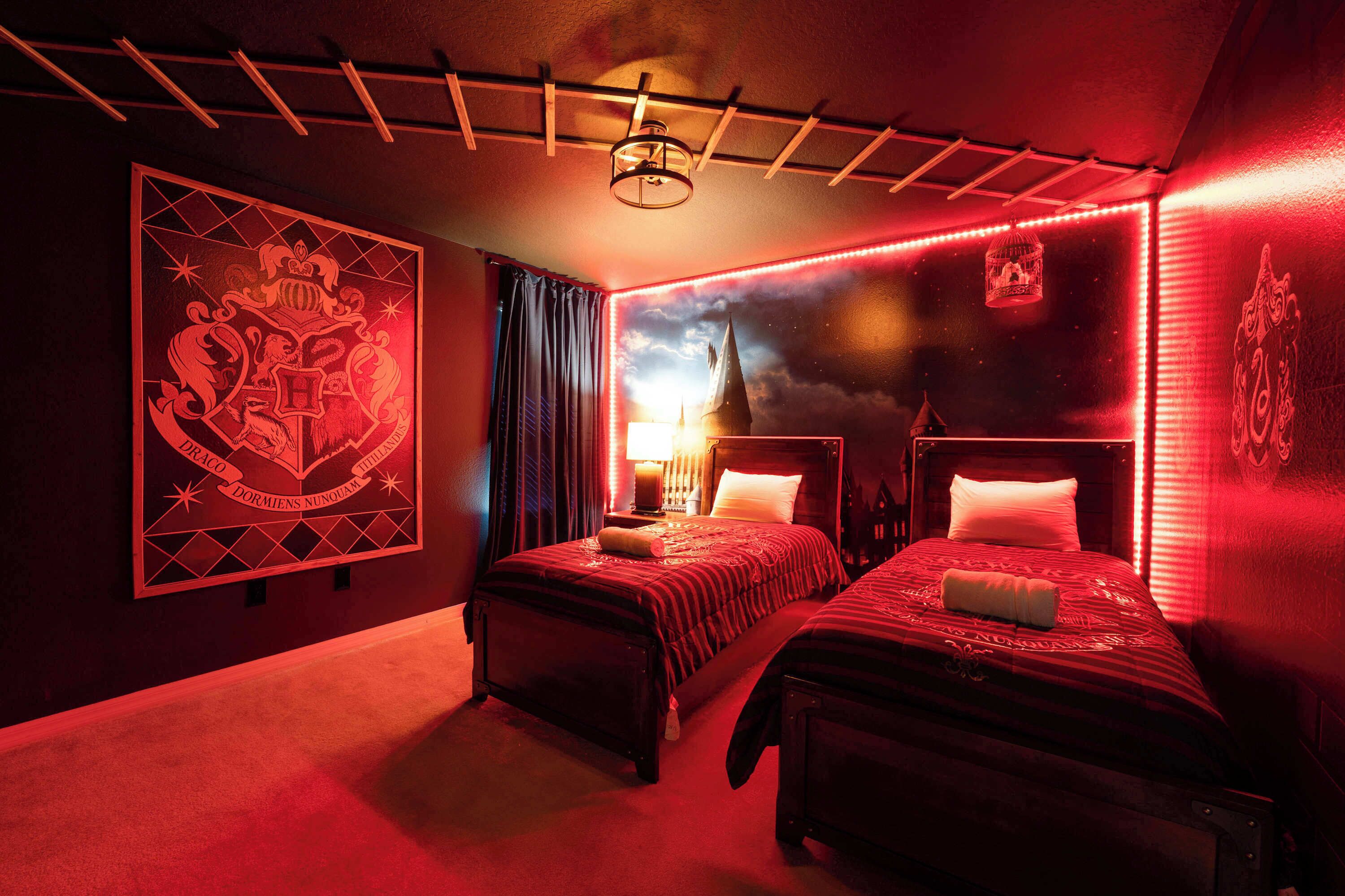 A room with two beds, a large wall mural, a ceiling light fixture, and a window with curtains.