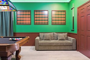 A pool table with balls, a sofa, and three patterned wall decorations. - Themed Disney Home w/ Pool & Game Room (Kissimmee)