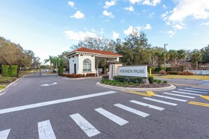 A gated entrance with a sign reading 'VERANDA PALMS' and a small building with a red roof. - Themed Disney Home w/ Pool & Game Room (Kissimmee)