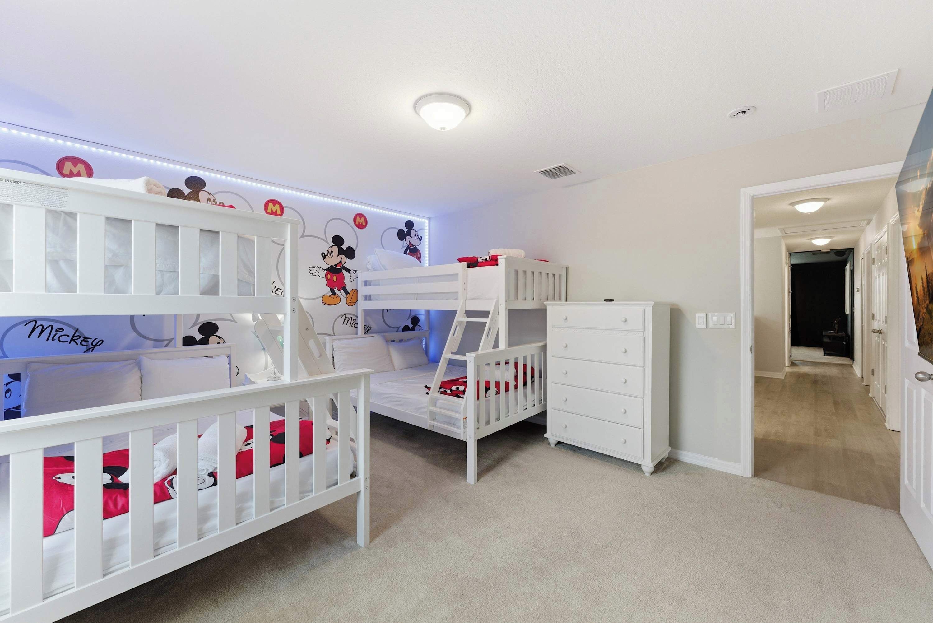 A child's room with bunk beds, a dresser, and Mickey Mouse wall decals.