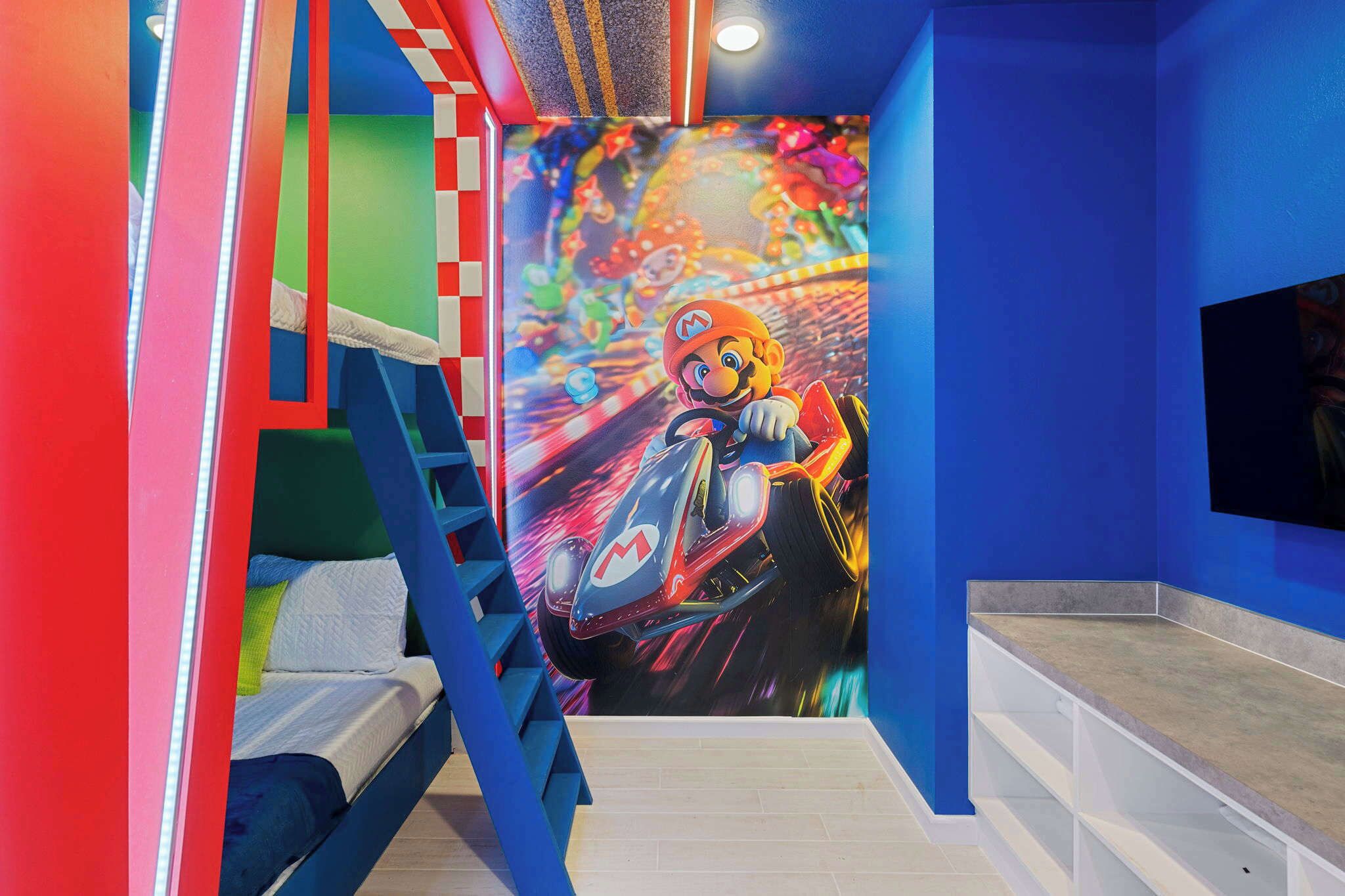 Une chambre avec un lit superposé, une fresque murale représentant un personnage de jeu de course et un téléviseur fixé au mur.