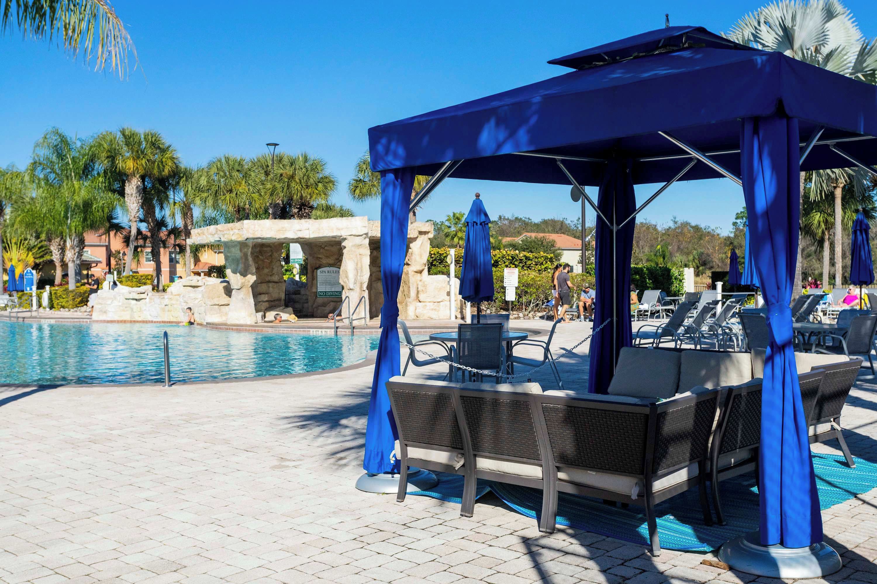 A poolside area with a covered seating area, lounge chairs, and a stone structure.