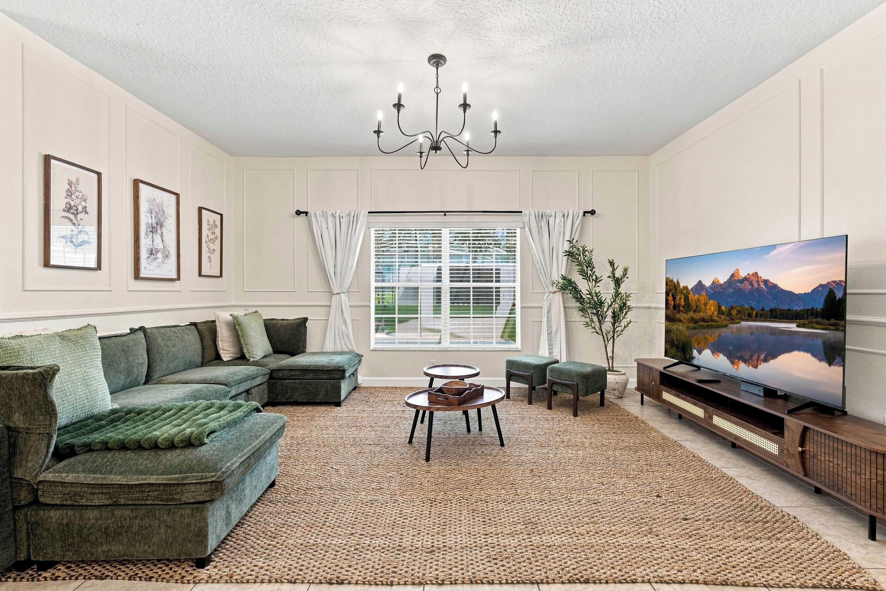 A living room with a sectional sofa, a coffee table, a television, and framed artwork on the walls.