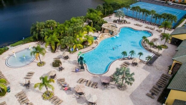 A resort with a large pool, lounge chairs, and palm trees. - Family-friendly Paradise Palms Townhouse With Pool Access (Kissimmee)