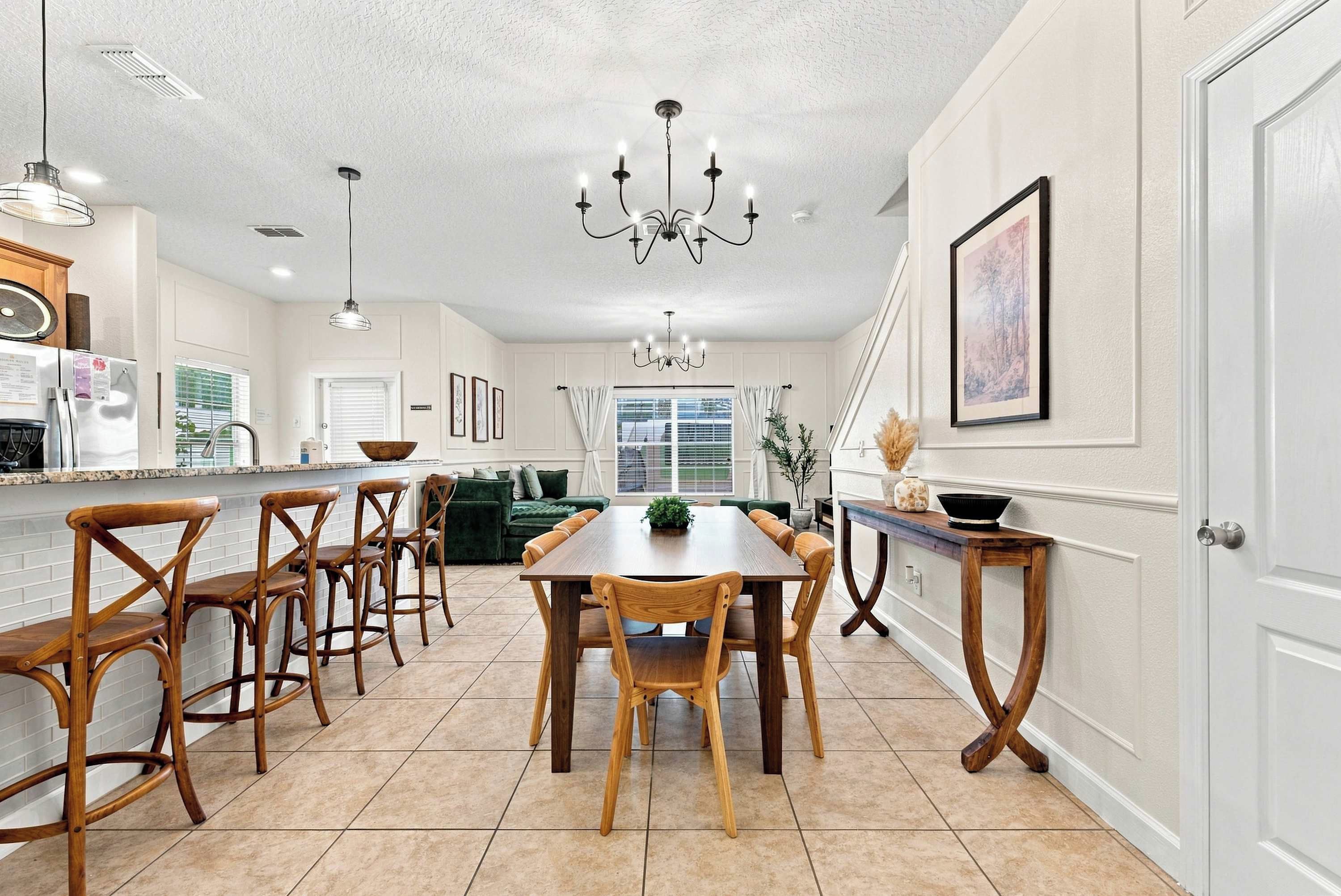 Une cuisine spacieuse avec un coin repas, comprenant une grande table et des chaises en bois, un lustre et une vue sur le salon.